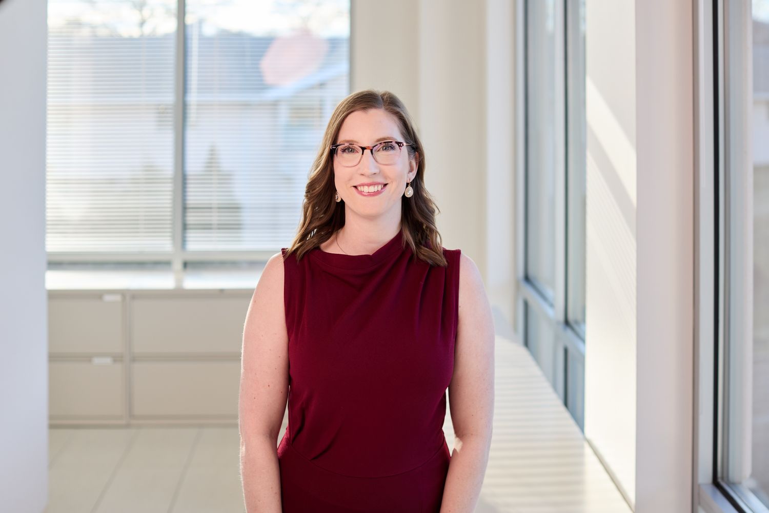 Smiling woman in a burgundy dress, bright office.