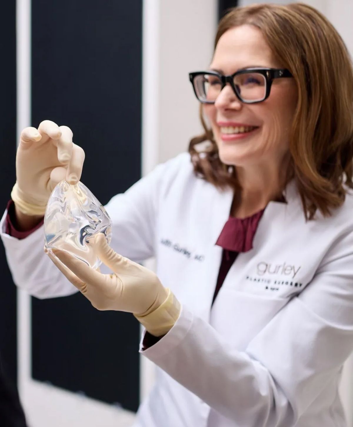 Doctor holding a silicone breast implant in clinic.