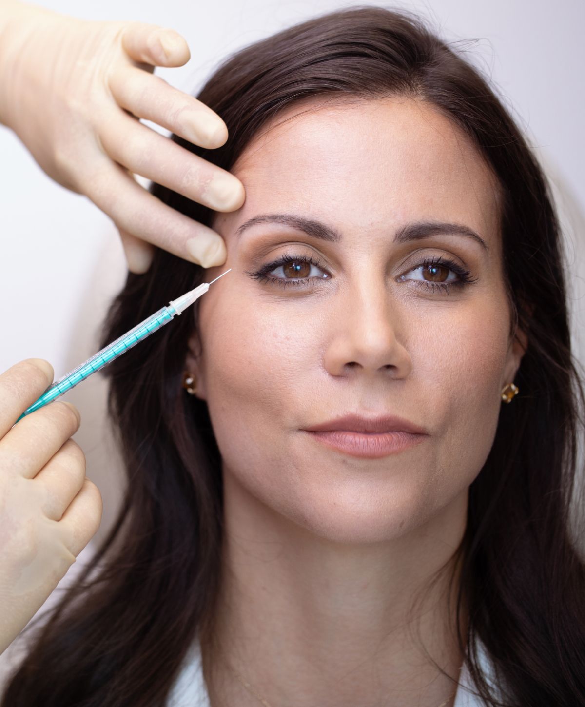 Woman receiving cosmetic injection in facial treatment.