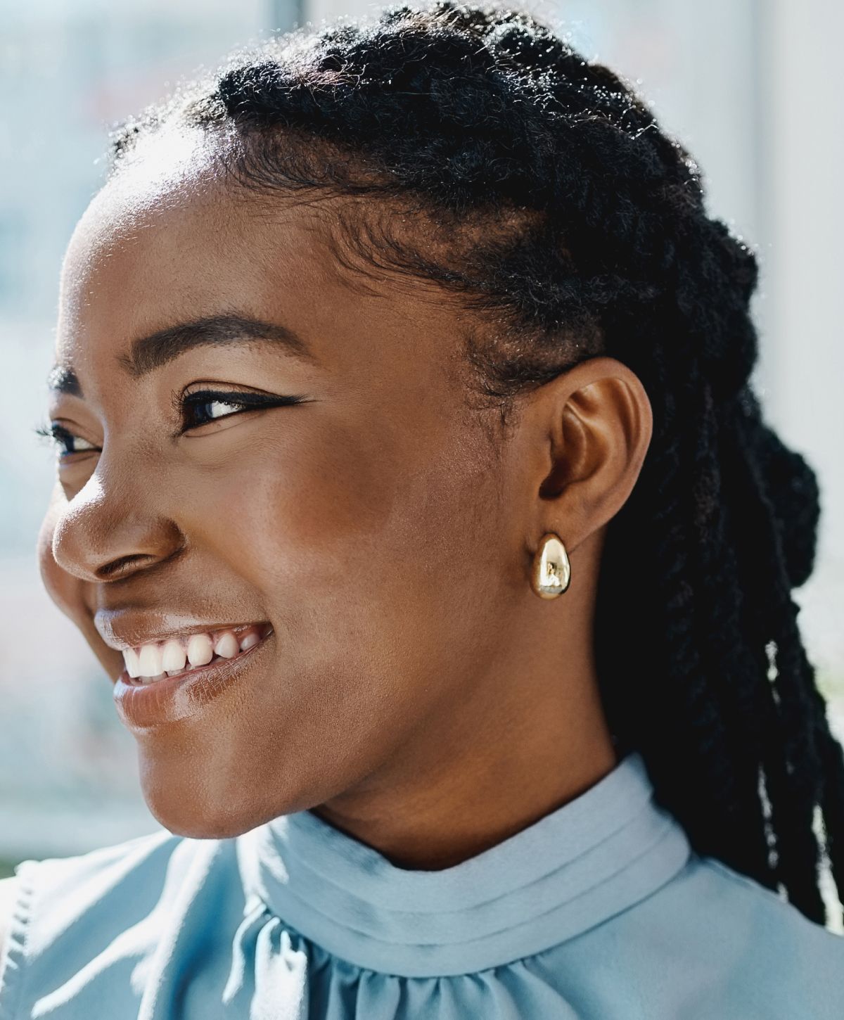 Woman smiling with natural hair and earrings.