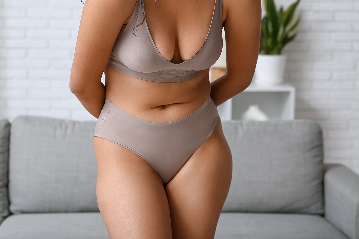 Woman in brown lingerie, standing indoors.