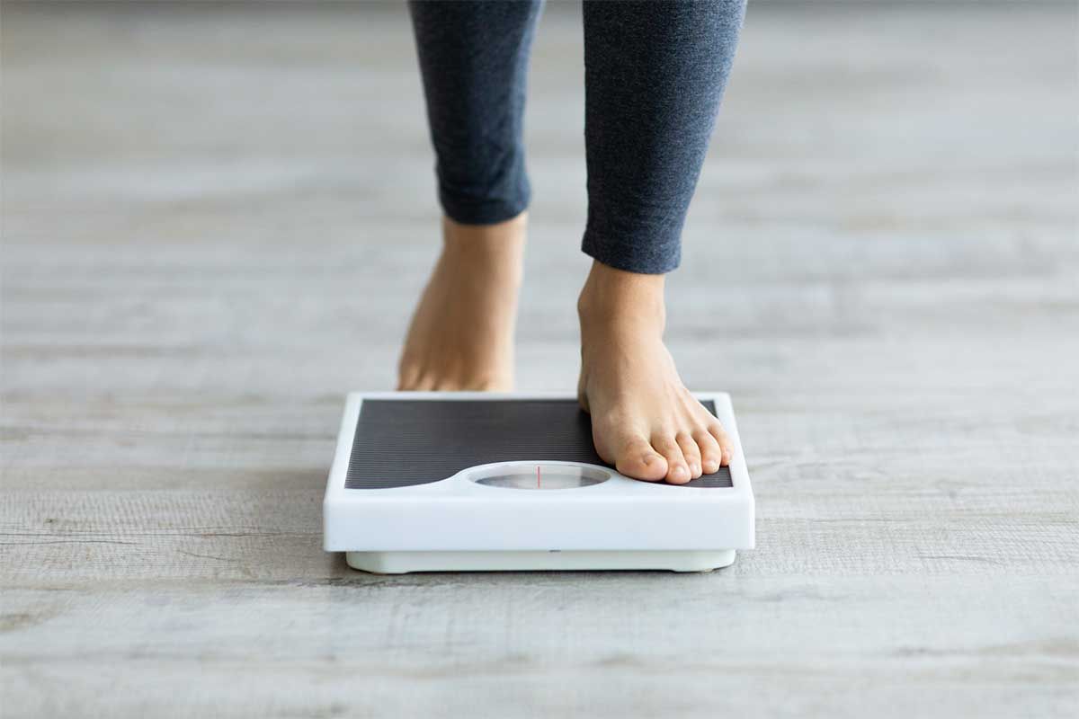 Person weighing themselves on a bathroom scale.