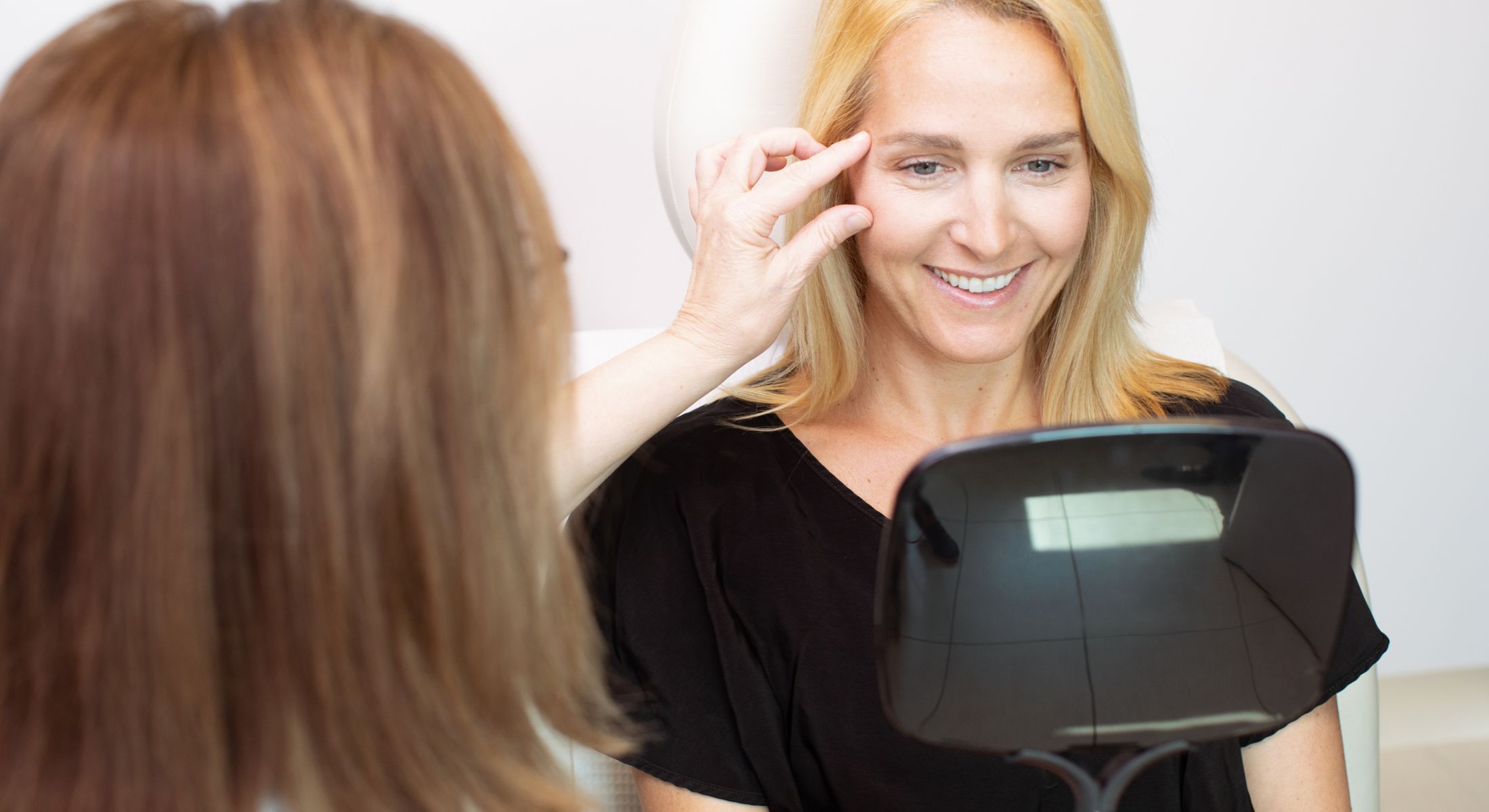 Woman smiles while receiving skincare consultation.